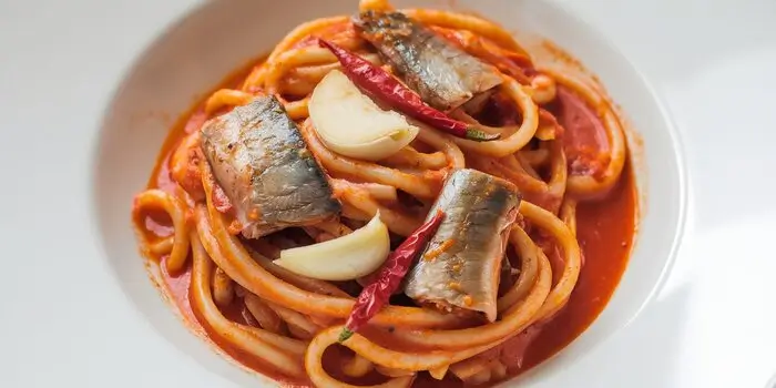 A plate of sardine pasta with garlic and chili, highlighting the vibrant and savory flavors of the dish.